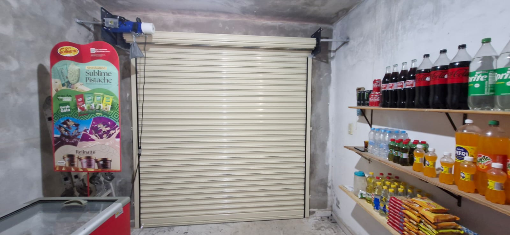 Porta de enrolar bege instalada no interior de mercadinho comercial